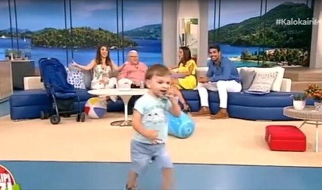 Απολαυστικό στιγμιότυπο! Ο Κώστας Βουτσάς δίνει συνέντευξη και o γιος του, Φοίβος παίζει