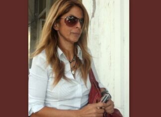 Η Νίκη Βίσση φωτογραφίζεται μπροστά από το καμένο της σπίτι στο Μάτι